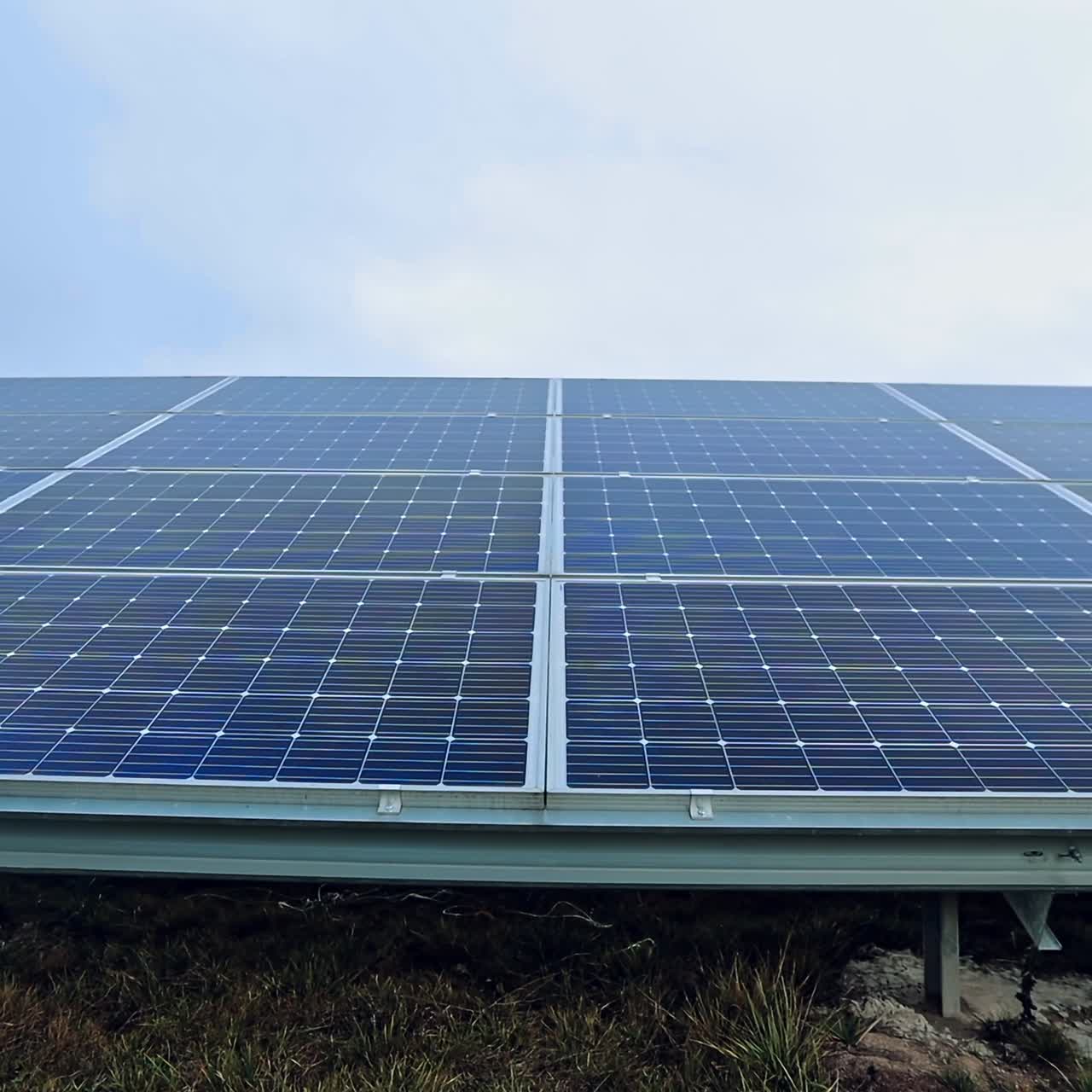 Blue solar panel under the clear sky. Photovoltaic battery in the sunlight. Renewable energy. Close-up. Motion camera top down.