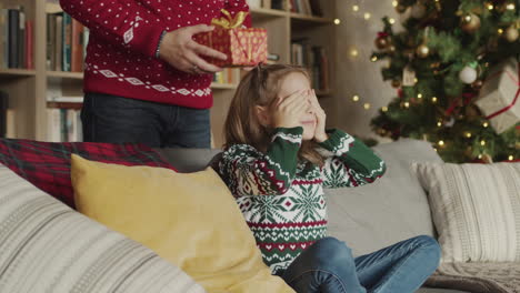 amoroso padre dando un regalo sorpresa a su pequeña hija el día de navidad en casa