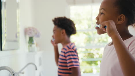 Hermano-Y-Hermana-Sentados-En-El-Baño-En-Casa-Cepillándose-Los-Dientes-Juntos