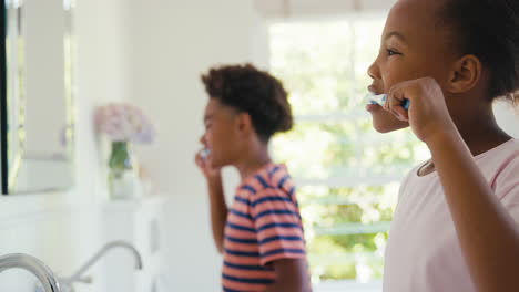 hermano y hermana sentados en el baño en casa cepillándose los dientes juntos