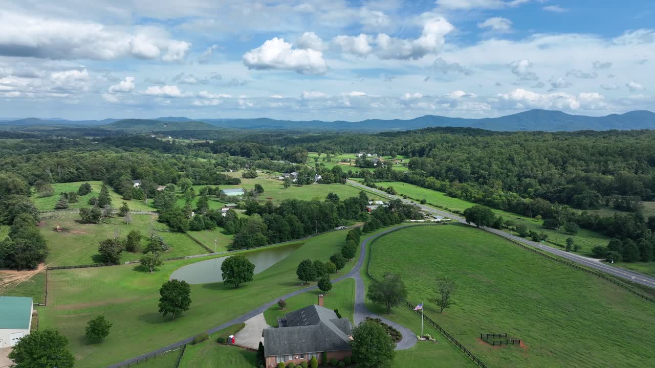 Charming American farmstead with house, waving flag of USA and large property. Rising drone wide shot. Rural area of viginia with traffic on highway in distance. Summertime in suburbia