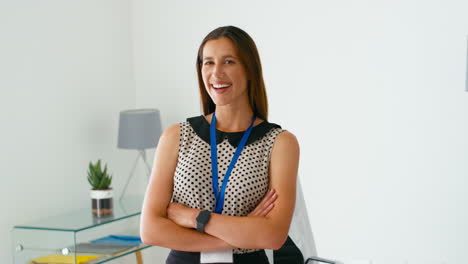 Portrait-Of-Smiling-Female-Doctor-Or-GP-Standing-By-Desk-In-Office