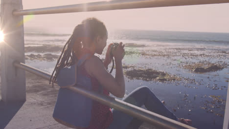 animación de puntos de luz sobre mujer biracial tomando fotos con cámara en el paseo marítimo