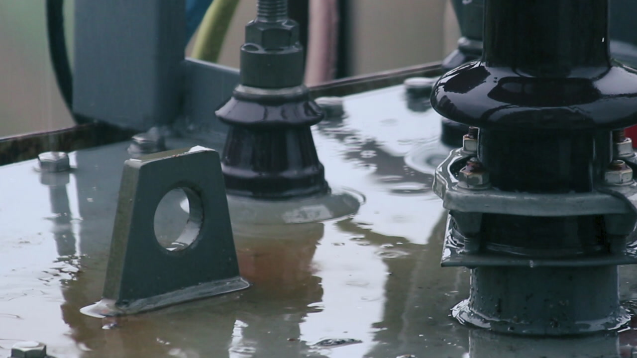 Close-up of rainwater on electrical transformer parts during rainfall, industrial weather footage, great for energy, climate, power, storm and infrastructure projects.