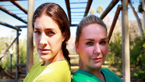 portrait of confident friends standing back to back during obstacle course