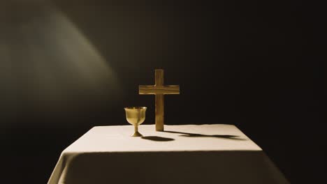 religious concept shot with wooden cross and chalice on altar in pool of light 2