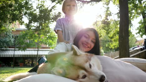 familia y mascota, joven madre e hijo sonríen con perro husky en el parque