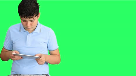 녹색 화면 배경에서 디지털 태블릿을 사용하는 십대 소년 4