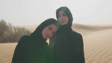 retrato de dos mujeres musulmanas en hiyab de pie en un desierto ventoso