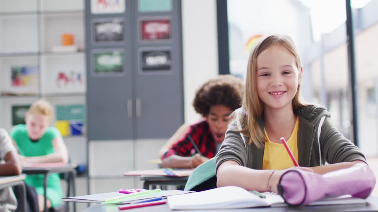 Portrait of happy diverse schoolchildren at desks in school classroom
