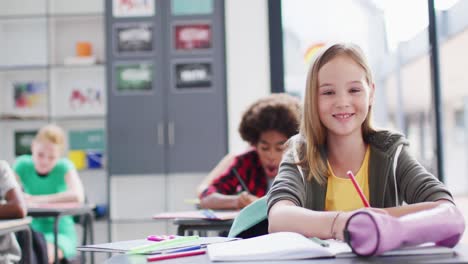 Porträt-Glücklicher,-Vielfältiger-Schulkinder-An-Schreibtischen-Im-Klassenzimmer