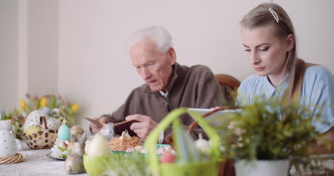 panning shot of father praying while daughter using digital tablet at table during easter