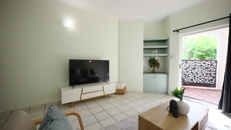 pullback above wooden veneer chair and coffee table of small modern tiled apartment loungeroom, sliding door to balcony outside