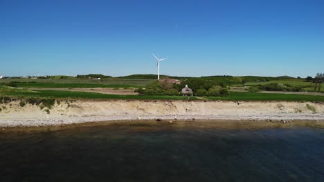 4k aerial of danish coastline with a small cliff and green fields