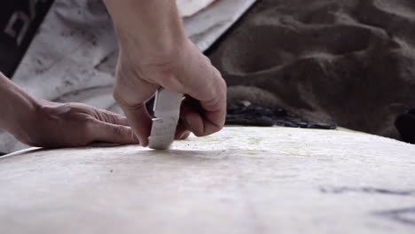 hand waxing surfboard with a bar of wax to provide the surfer grip and traction