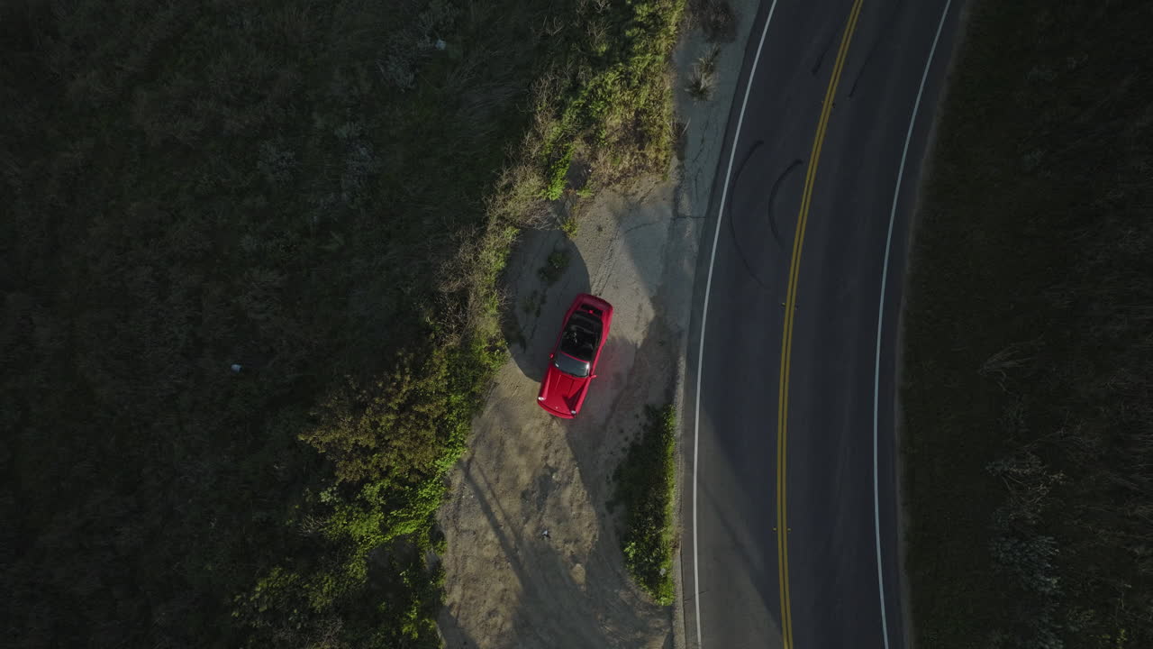 Filmagem aérea de drone eleva-se e gira de cima para baixo sobre um Porsche 1993 Carrera S vermelho perto de um cânion.
