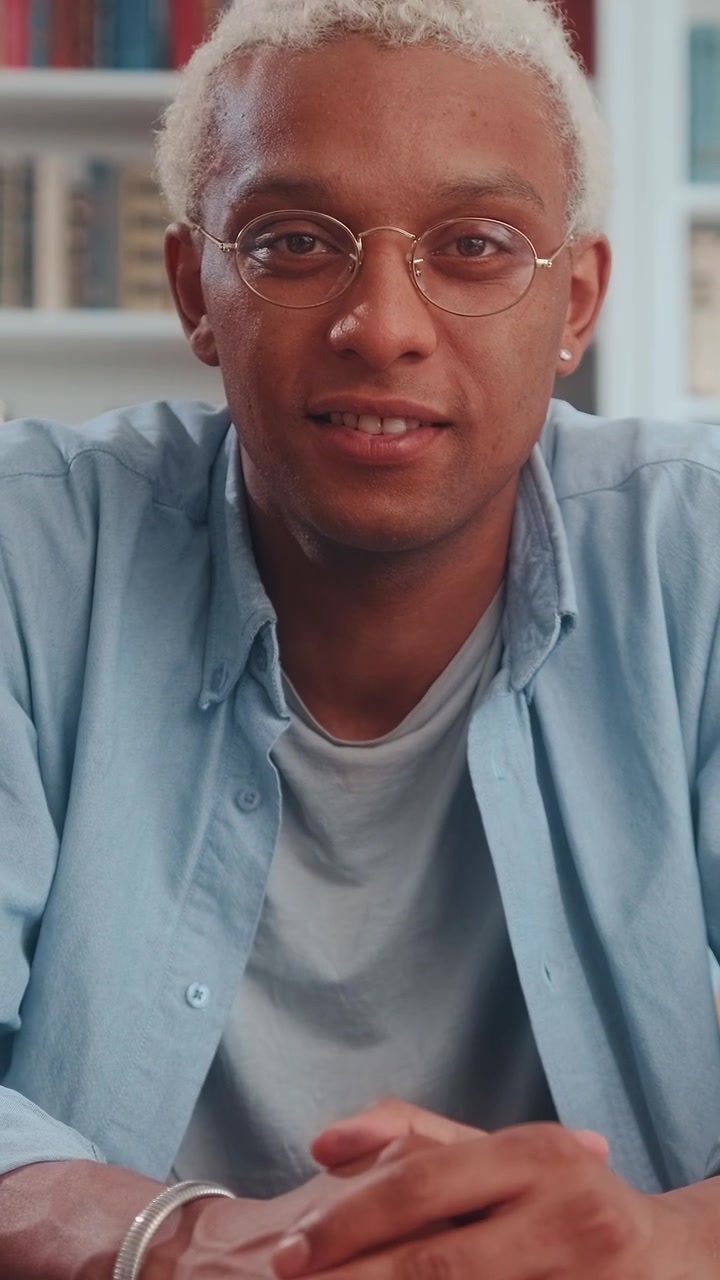 Ritratto di un giovane uomo afroamericano biondo con occhiali rotondi che guarda il