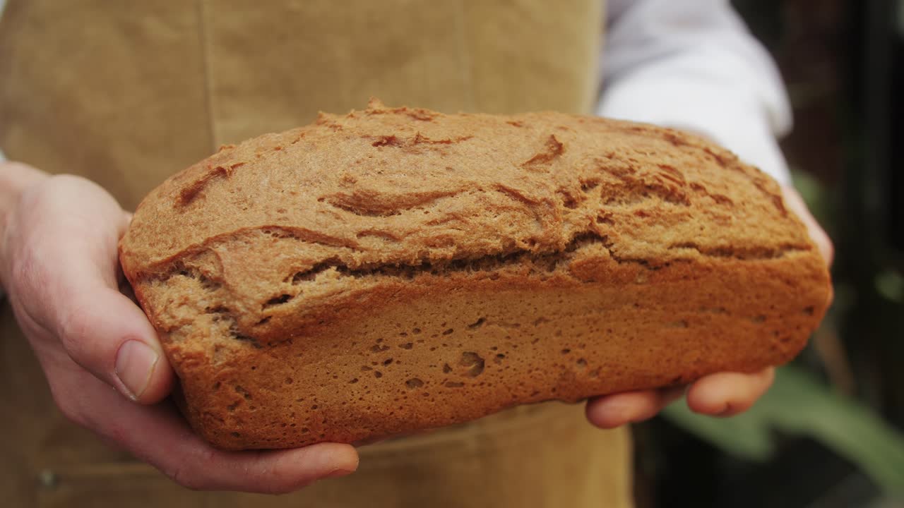 The baker holds in hands a of fresh bread close-up. Artisan bread is making by skill bakers using natural and high-quality ingredients. Food with health and flavour benefits.