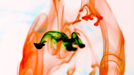 slow motion flow of green and orange ink droplets falling into water