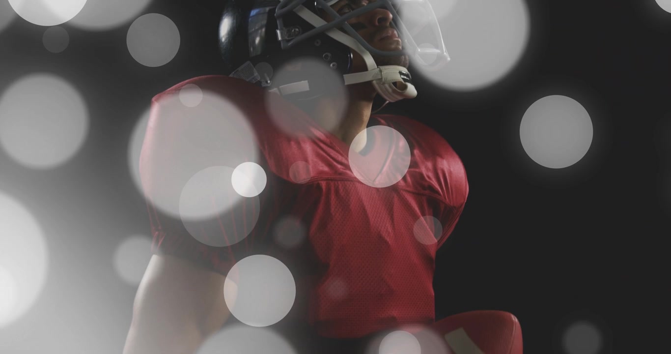 Giocatore di football maschio che cambia la presa e culla il pallone mentre la telecamera si alza, con bokeh che mostra la preparazione sportiva.