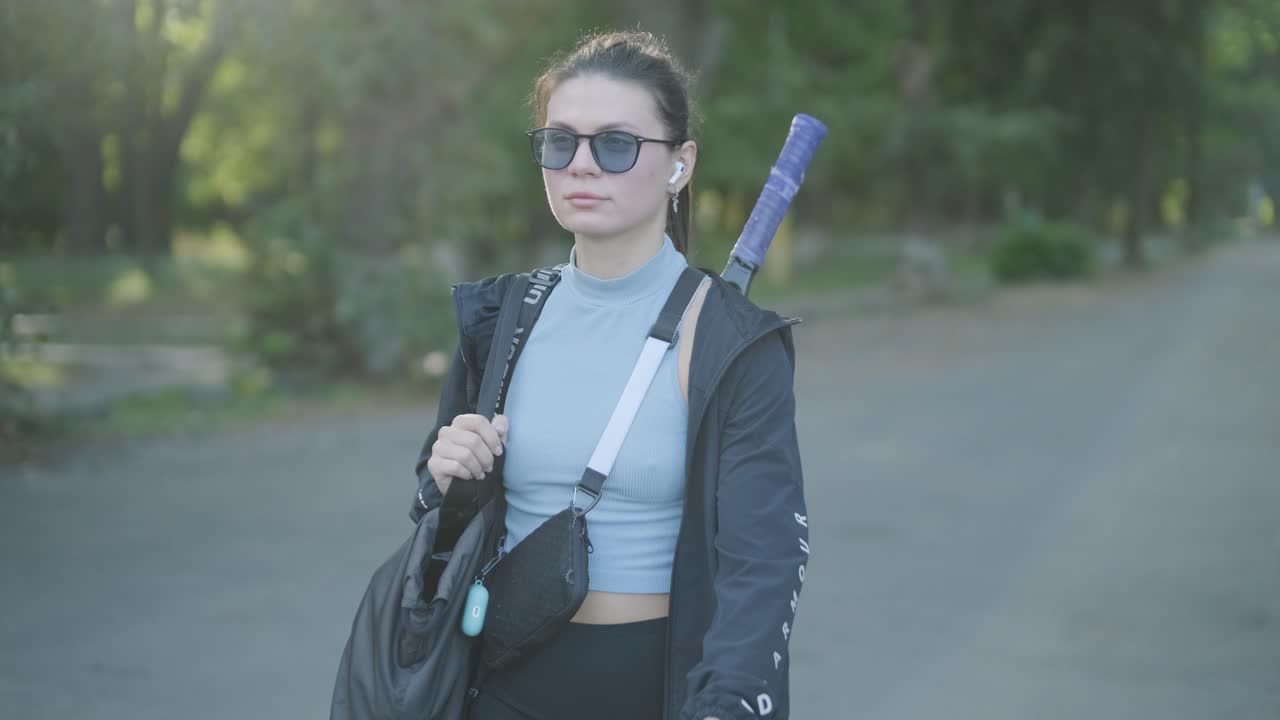 jugadora de tenis caminando con bolsa de engranajes y raqueta