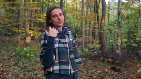 Young-woman-plays-with-hair-on-the-background-of-autumn-scenery