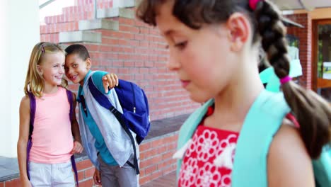 un escolar intimidando a una chica triste en el corredor de la escuela.