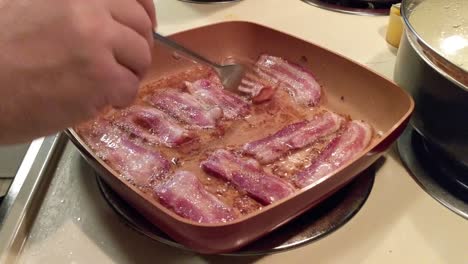tocino sin curar cocinado en una sartén cuadrada en una estufa eléctrica
