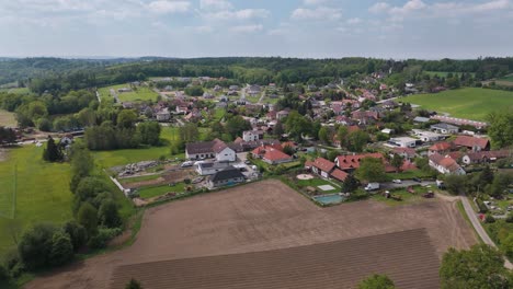 Flying-towards-a-czech-village-Nechánice-with-a-field-and-a-pond-in-foreground