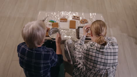 grandmother and granddaughter making gingerbread houses