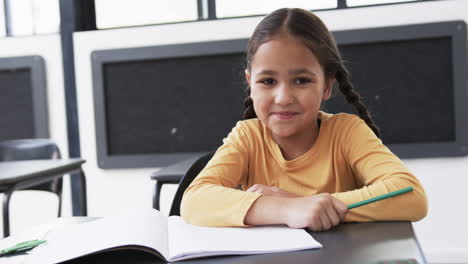 En-Un-Ambiente-Escolar,-Un-Joven-Estudiante-Birracial-Se-Sienta-En-Un-Escritorio