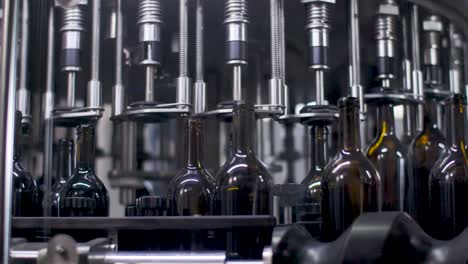 Wine-Bottling-Machine---Empty-Glass-Bottles-Being-Filled-With-Wine-In-Automatic-Machinery