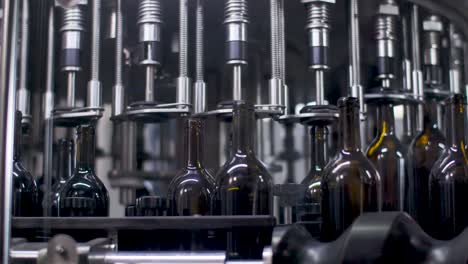 wine bottling machine - empty glass bottles being filled with wine in automatic machinery