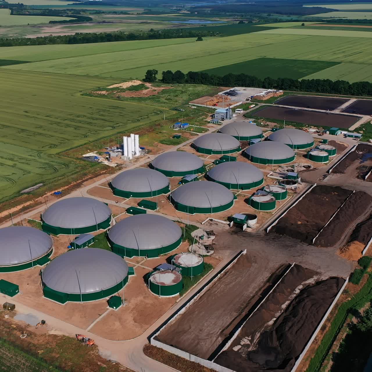 Modern agribusiness plant for green fuel production. Futuristic biogas complex locating in vast fields. Aerial perspective