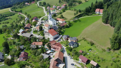 establishing aerial shot above a small town with church in prevalje slovenia