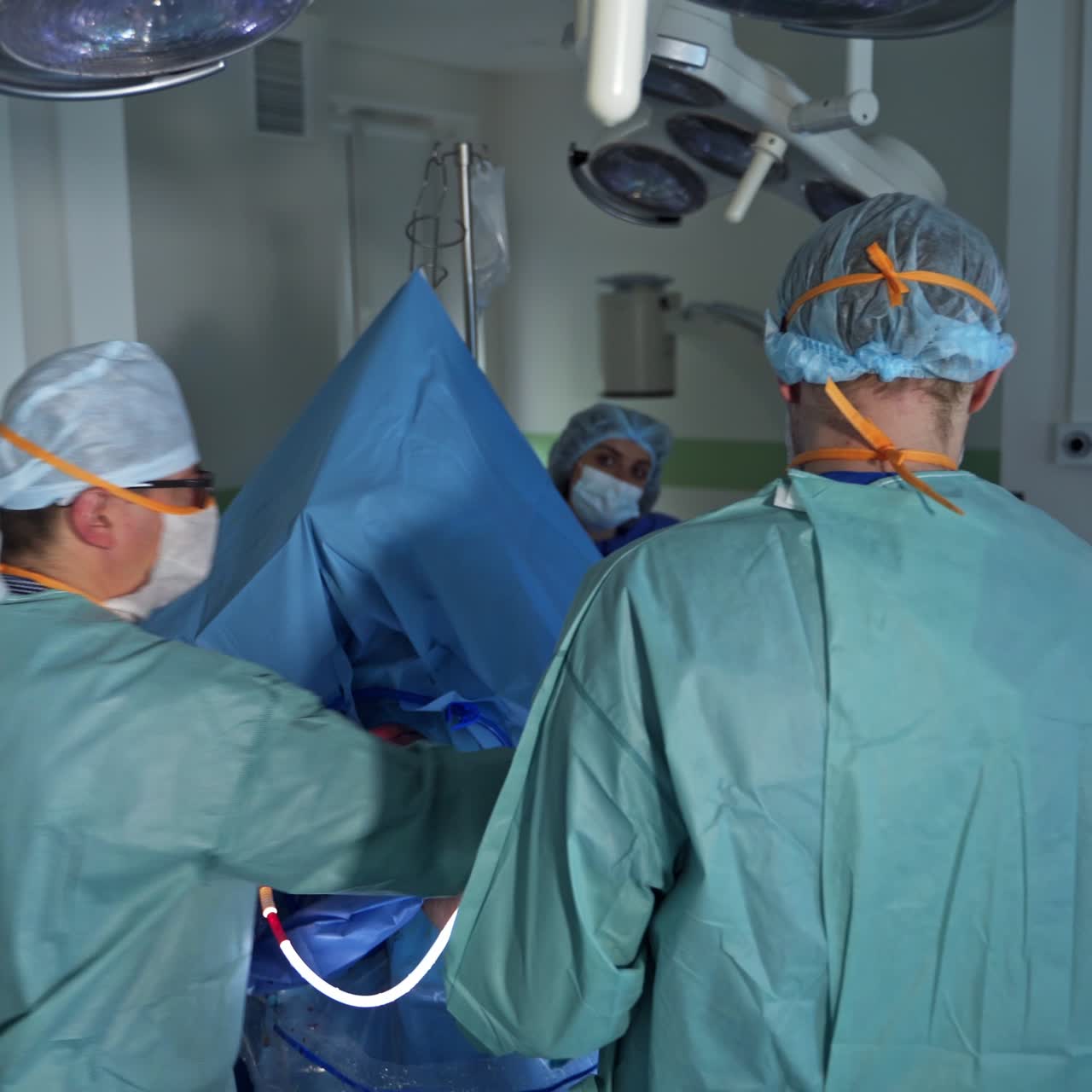 Medical care team operating the patient with special device. Professionals follow the screen showing inner organs