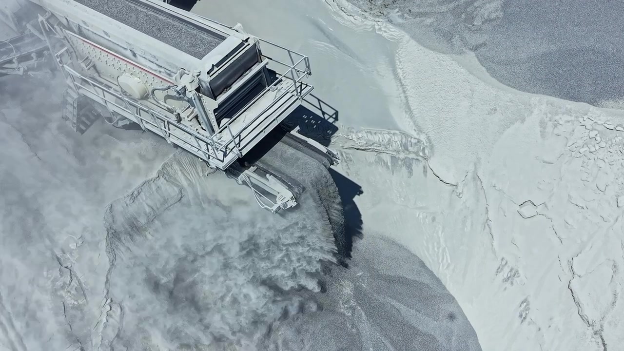 Heavy machinery works in granite quarry for extracting stone materials during daylight with dust and movement in the background