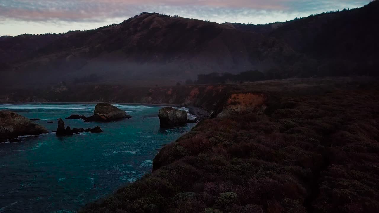 Twilight aerial view of ocean cliffs and beach waves at Sand Dollar Beach in Big Sur California