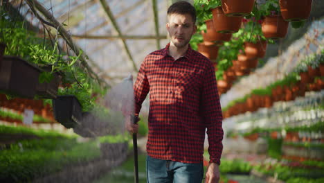 gardener watering flowers in greenhouse