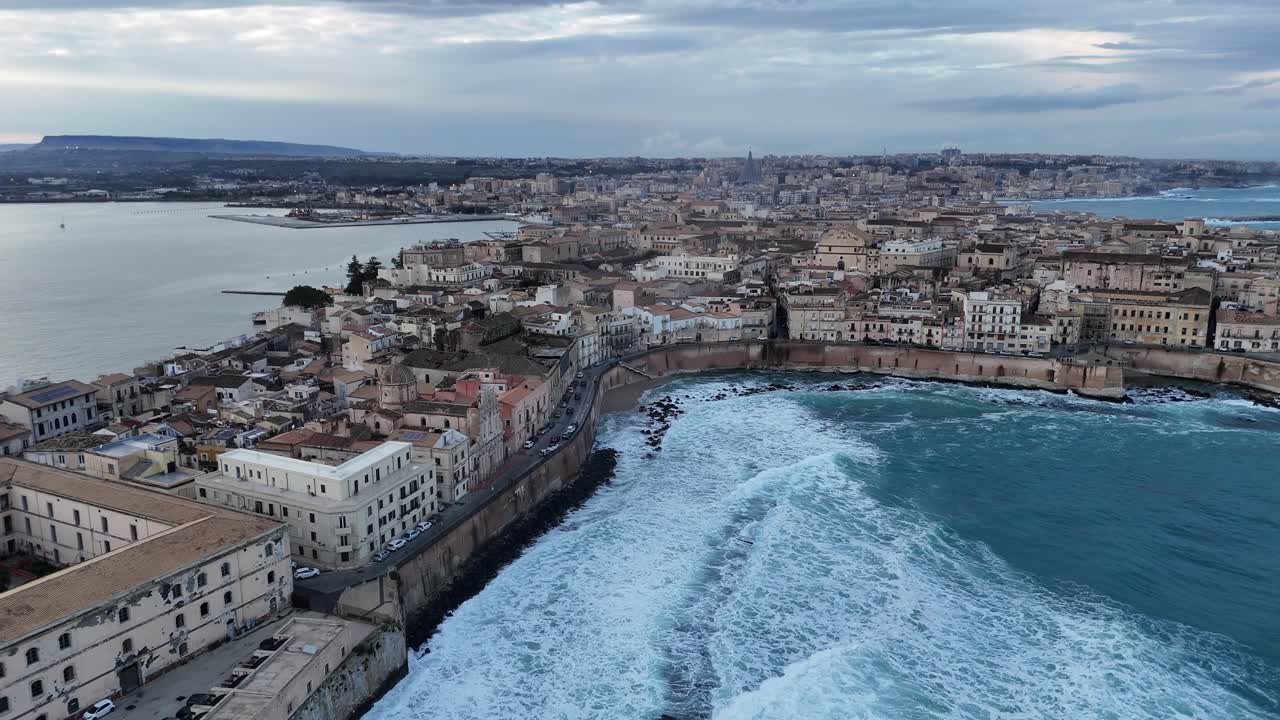 Large plan panoramique aérien par drone de l'île d'Ortigia à Syracuse, Sicile. Le centre historique est entouré par la mer Méditerranée, avec la ville moderne et les montagnes en arrière-plan