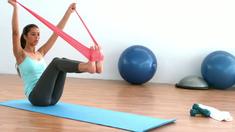 fit brunette stretching using resitance band in studio