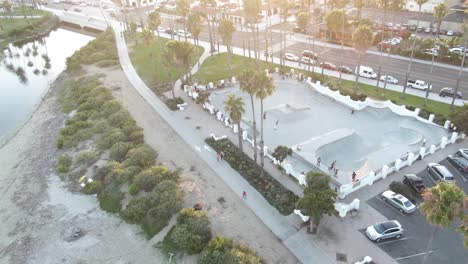 antena circular número 4 de un parque de patinetas durante la puesta de sol con adultos jóvenes cerca de la playa y la transitada autopista en santa bárbara, california, ee.uu.