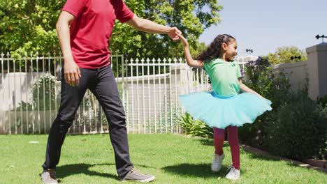 happy biracial father and daughter dancing in garden together