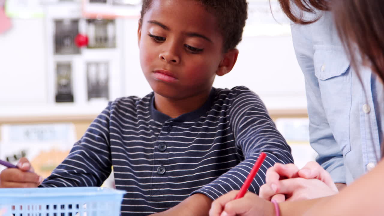 Insegnante che aiuta uno scolaro della scuola elementare durante la lezione d'arte.
