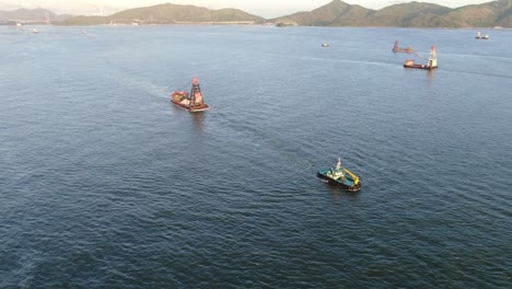 tugboat pulling a small barge in hong kong bay, aerial view