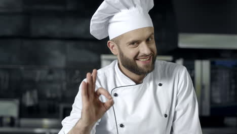 chef feliz haciendo ok gesto en la cocina profesional