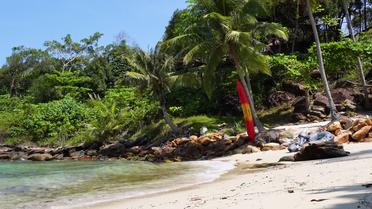 una playa encantadora y tropical rodeada de palmeras y olas del mar, en el fondo hay un kayak y un pequeño bote a motor, ubicado en la isla de koh kood en tailandia en asia