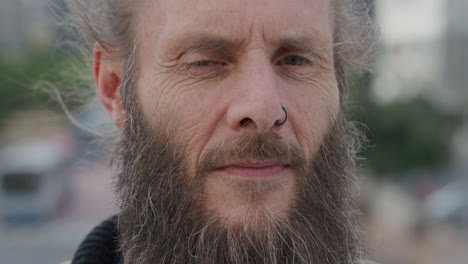 close up portrait mature bearded hippie man looking pensive turns head independent urban lifestyle in city wearing nose ring wrinkles aging