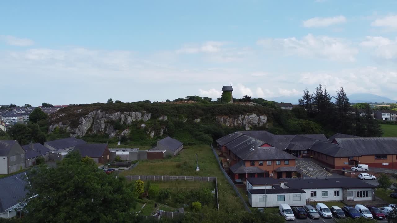 molino de viento en desuso llangefni cubierto de hiedra en la ladera del punto de referencia vista aérea ascendente, anglesey
