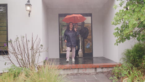 Una-Familia-Que-Sale-Corriendo-De-La-Casa-Bajo-La-Lluvia